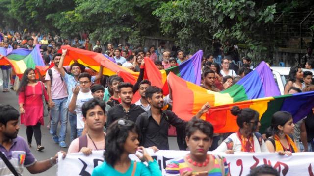 pessoas na rua com bandeira gay na Índia