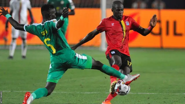 Umukinnyi wa Uganda (iburyo) arimo guhatanira umupira n'umukinnyi wa Senegal mu mukino wa CAN ya 2019