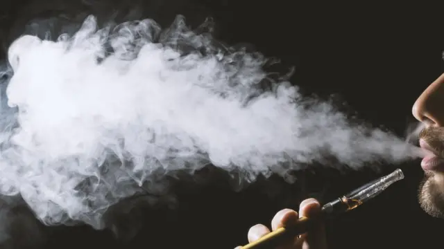 Hombre fumando cigarrillo electrónico.