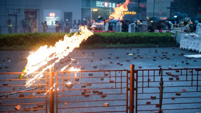 一些示威者投郑燃烧弹，掉落在警察和示威者防线中间的位置。