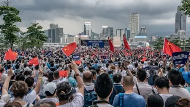 Para demonstran mengibarkan bendera China dalam aksi unjuk rasa di Taman Tamar, Hong Kong