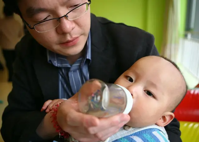 Un père nourrit son fils au biberon