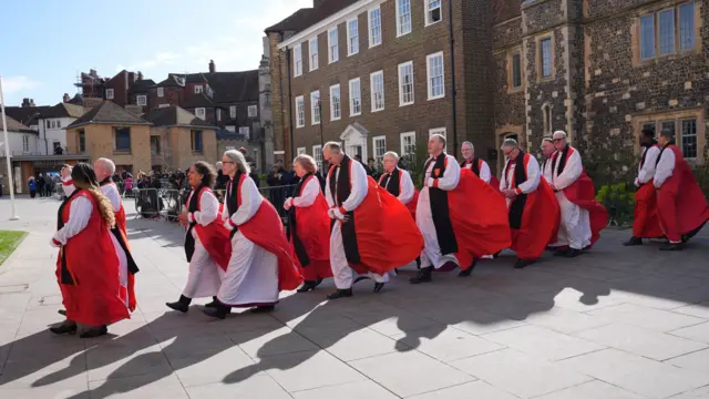 Members of di clergy waka through one courtyard for a line of two rows