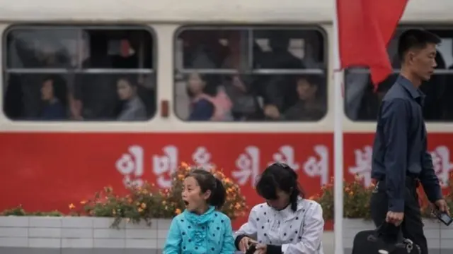 प्योंगयांग रेलवे स्टेशन के बाहर बैठे लोग