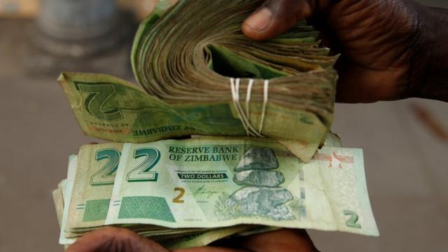 Un vendeur à Harare avec d'anciens billets de 2 dollars et de nouveaux billets de 2 dollars zimbabwéens en novembre - Zimbabwe