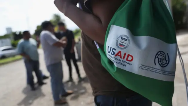 Migrante en la frontera de Honduras con una bolsa de USAID.