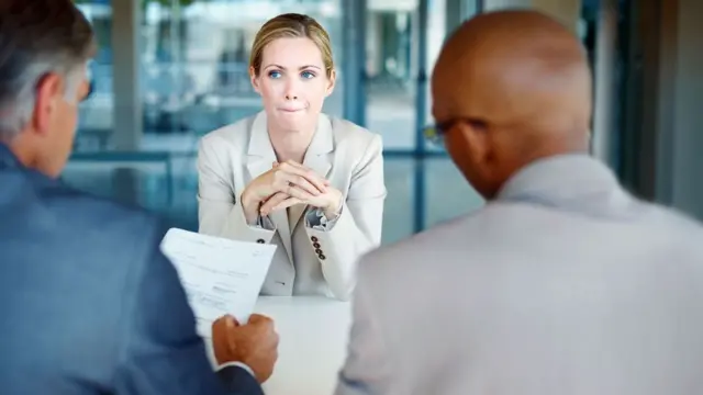Mulher sendo entrevistada por dois homens para vaga de emprego