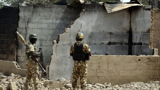 Awọn ologun duro niwaju àwókù ile kan