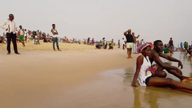 Couple sit down close to di water for beach