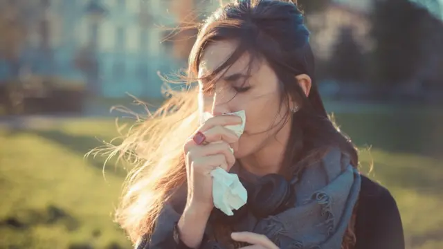 Una mujer sonandose la nariz