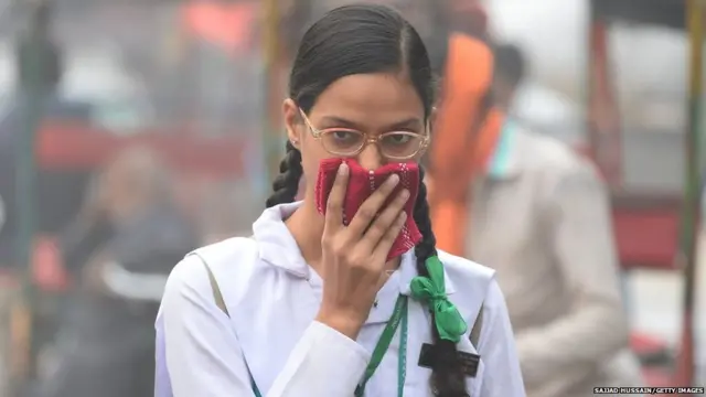 schoolgirl covers her face with a handkerchief amid heavy smog in the old quarters of New Delhi on November 8, 2017
