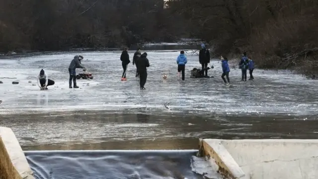 Los jóvenes juegan en una sección cubierta de hielo del río Esca en Burgui, provincia de Navarra, España, el nueve de enero de 2017.