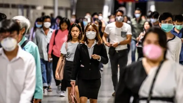 Commuters wearing facemasks amid fears of the spread of the COVID-19 novel coronavirus exit a metro station in Bangkok on March 4, 2020