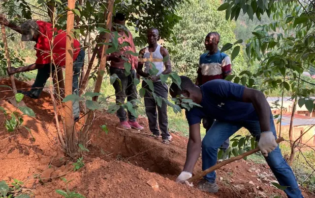 Umwe mu baje guhamba iyi mbwa yitwaje umusaraba ngo ajye yibuka aho bayishyize