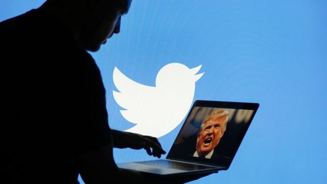 Una persona sujeta una computadora con la imagen de Donald Trump.