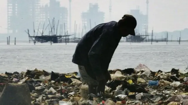 Seorang pemulung tengah mencari sampah di pantai Jakarta.