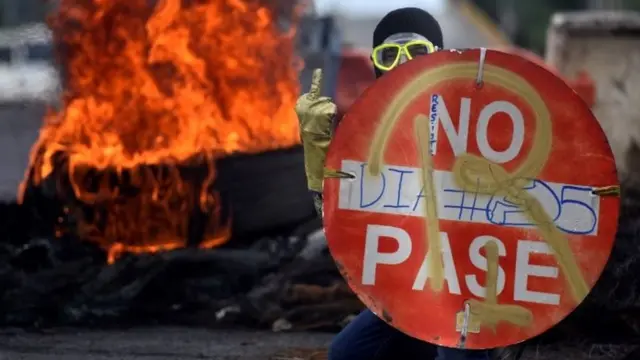 Um manifestante nos protestosvalsports palpitesCali com fogo por trás.