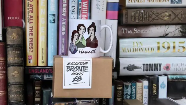 Libros y taza con las figuras de las hermanas Brontë