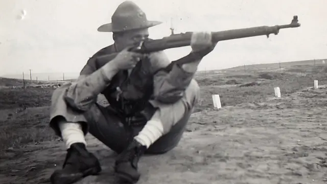 Charles Morse, em foto de 1941, sentado no chão e com sua arma apontada