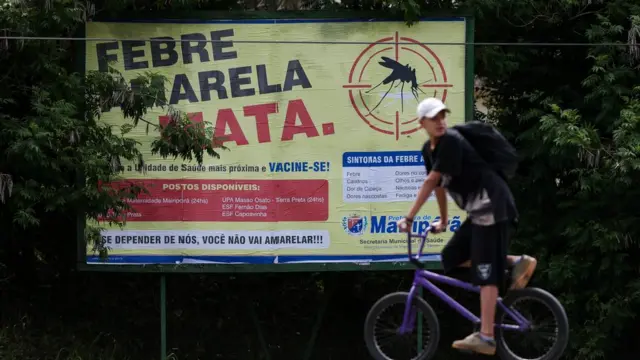 Homem passacasino300frente a placa que diz 'Febre amarela mata'