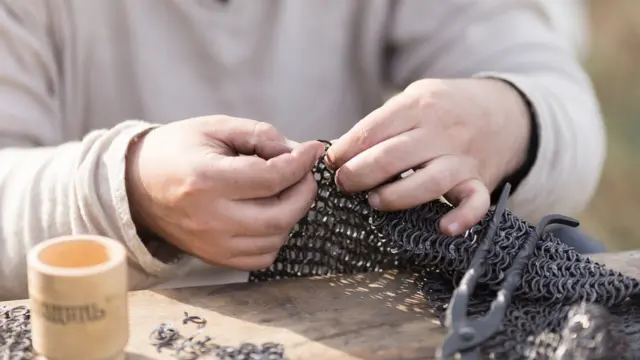 Руки человека, изготовляющего кольчугу