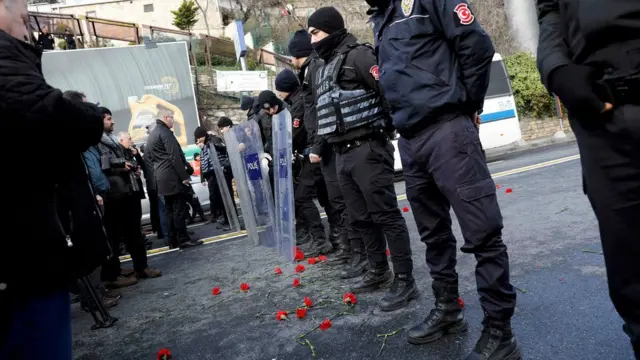 Flowers are placed next to Turkish police officers as they stand guard near the Reina nightclub, which was attacked by a gunman, in Istanbul, Turkey, on 1 January 2017