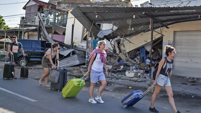 Wisatawan asing menyeret koper pascagempa di Kecamatan Pemenang,Tanjung, Lombok Utara, NTB, Senin (6/8).