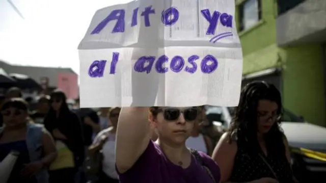 Una mujer levanta una pancarta con el mensaje "Alto ya el acoso".