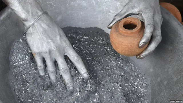 Indian worker puts gun powder inside a clay pot to make a firecracker for the upcoming Diwali festival at a workshop in Champahati