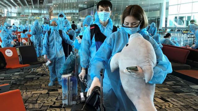 A Vietnamese woman carries a stuffed animal while boarding a repatriation flight from Singapore to Vietnam amid spread of the coronavirus disease (COVID-19) outbreak at Changi airport, Singapore August 7, 2020.