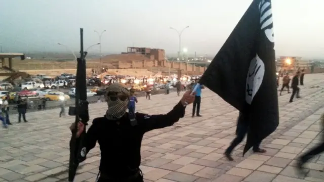 Combatente do EI com arma e bandeira (arquivo)