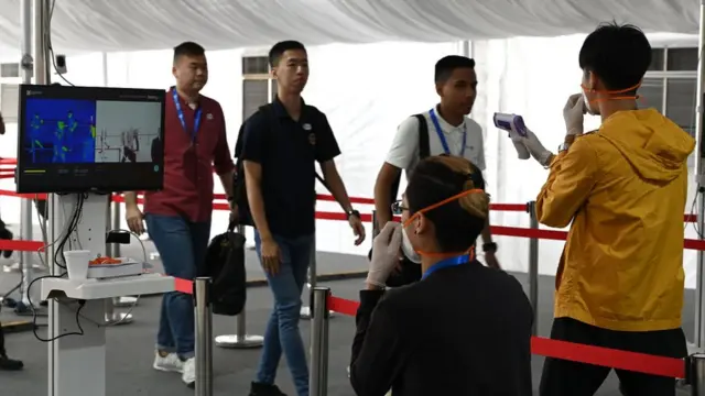 Personas revisan la temperatura de visitantes en Singapur