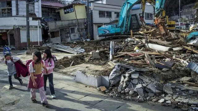 Garotas caminhampoker sfrente a destroços na áreapoker sFukushima