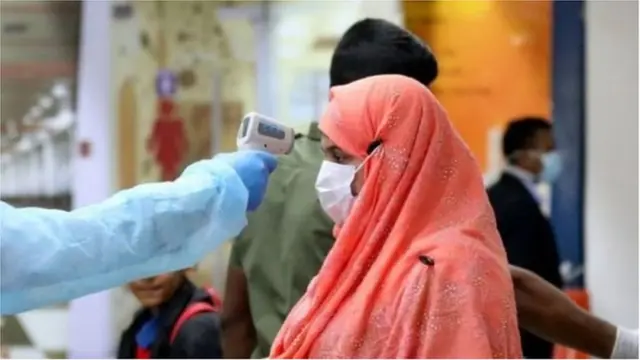 বিমানবন্দরে একজন যাত্রীর তাপমাত্রা পরীক্ষা করা হচ্ছে