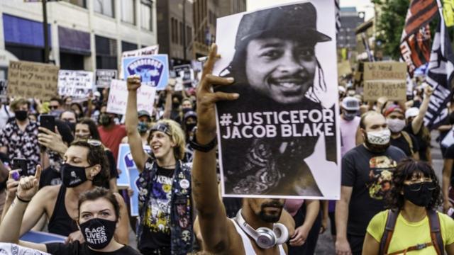 明尼苏达州明尼阿波利斯市群众举着威斯康辛州基诺沙市警察枪击案伤者雅布各·布莱克（Jacob Blake）照片游行声援（24/8/2020）
