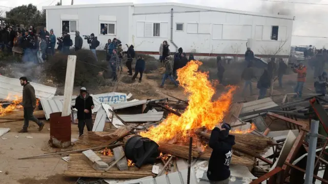 Dadka mudaaharaadaya ayaa alaabo gubay iyadoo ay booliisku galayaan aagaas