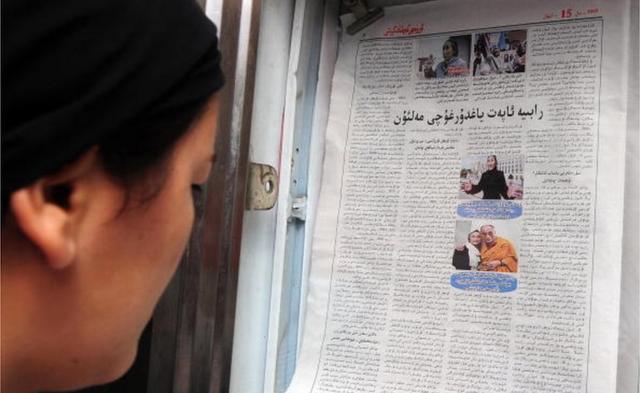 新疆的維族女性在看刊有熱比婭和達賴喇嘛照片的維文報紙。