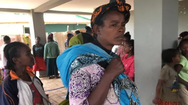 ከተፈናቃዮቹ መካከል መካከል የሆነች አንዲት እናት ልጇን እንዳዘለች በወረዳ 11 ወጣት ማዕከል ውስጥ ተጠልላለች