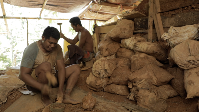Seorang warga memecahkan bebatuan di pertambangan emas tanpa izin di Bowone, Kepulauan Sangihe.