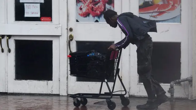 A man pushes a shopping trolley through the wind and rain in New Orleans