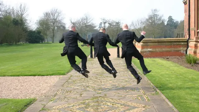 Трое мужчин в костюмах прыгают от радости