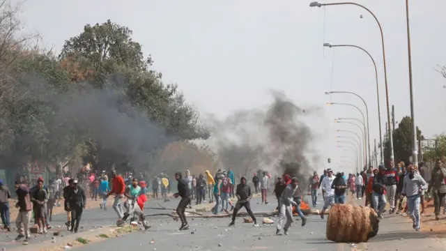 Des résidents affrontent des officiers de la police sud-africaine (SAPS) à Eldorado Park, près de Johannesburg, le 27 août 2020, lors d'une manifestation de membres de la communauté après qu'un garçon de 16 ans ait été déclaré mort.