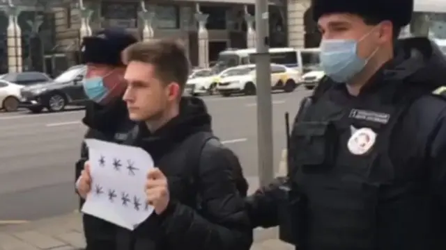 Privođenje čoveka koji nosi papir sa osam zvezdica