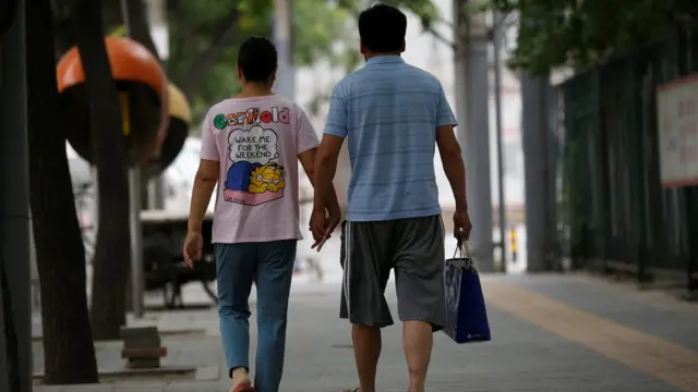 Dos ciudadanos chinos de espaldas. Caminan de la mano.