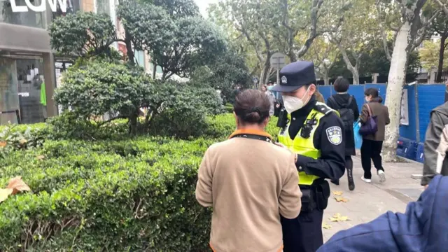 一名警察站在一名婦女身邊,而她正在從手機中刪除現場照片