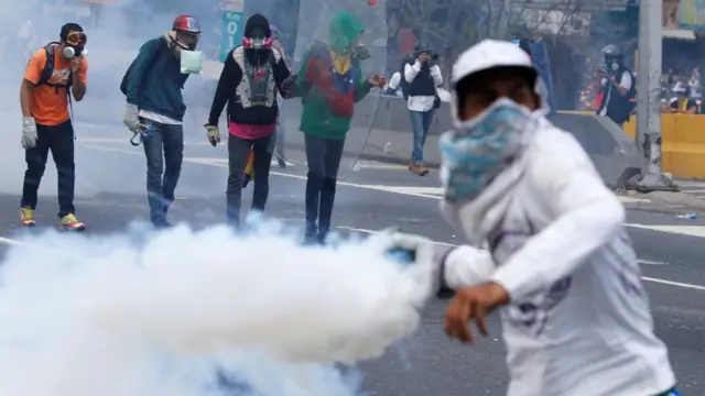 Joven devuelve un gas lacrimógeno a la policía.