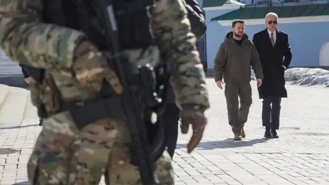 Zelensky and Biden with an armed soldier in the foreground