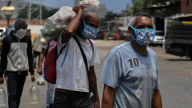 Hombres en Venezuela con mascarillas y alimentos.