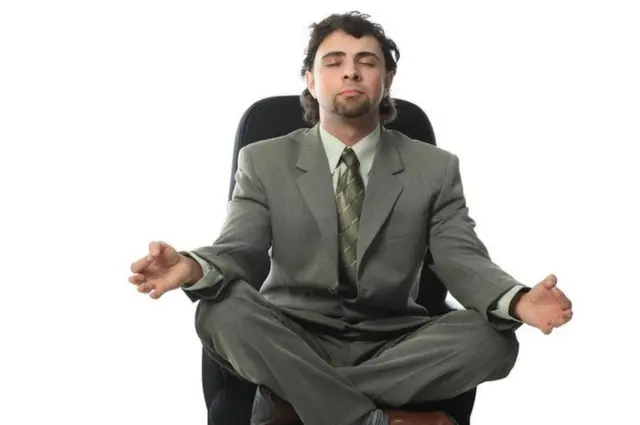 Una persona en pose de meditación en una silla de la oficina