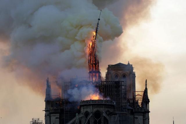 Падающий шпиль собора Нотр-Дам во время пожара.